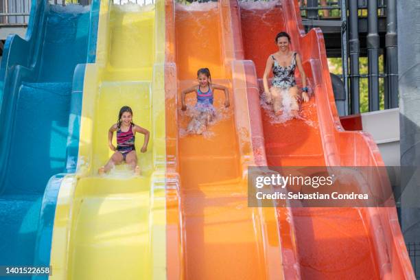 mother and daughters going down water slide. - wet stock pictures, royalty-free photos & images