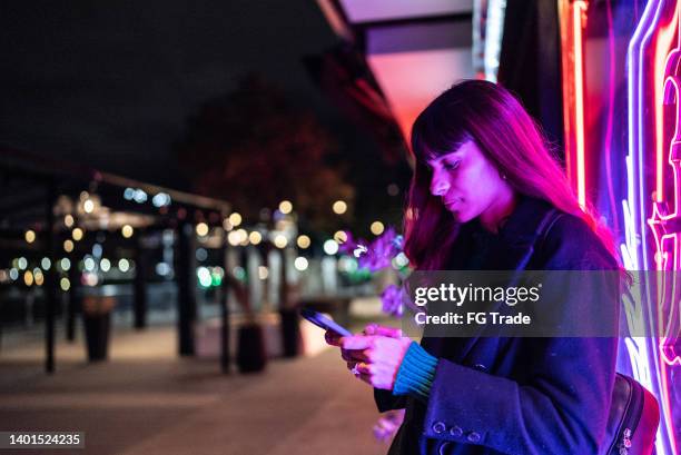 young woman using the mobile phone in the street - buenos aires night stock pictures, royalty-free photos & images