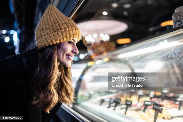 junge frau schaut auf eistheke - ice cream counter stock-fotos und bilder