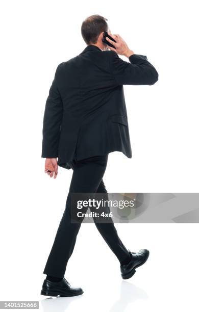 homme caucasien marchant devant un fond blanc portant des vêtements d’affaires et utilisant un téléphone intelligent - homme costume photos et images de collection