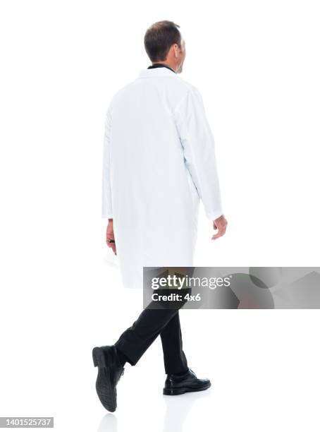 medico maschio caucasico che cammina davanti a uno sfondo bianco indossando un cappotto da laboratorio - back foto e immagini stock
