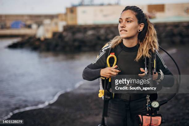 female diver standing on the beach in the wetsuit  near diving equipment - competitive diving stock pictures, royalty-free photos & images