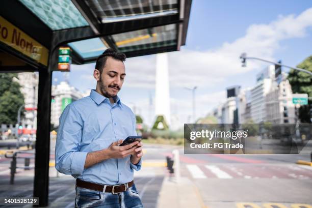 バス停で携帯電話を使う青年 - bus shelter ストックフォトと画像