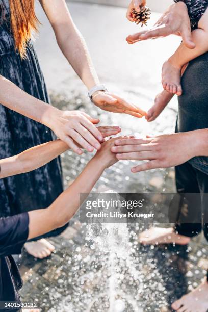 happy family spending time in the fountain on a hot summer day. - hands fountain water stock-fotos und bilder