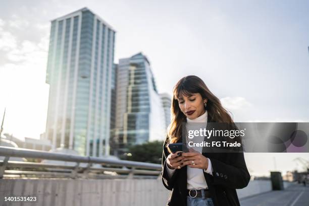 junge frau, die das handy auf der straße benutzt - puerto madero stock-fotos und bilder