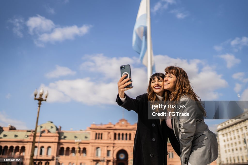 Women taking selfies on the mobile phone on the street