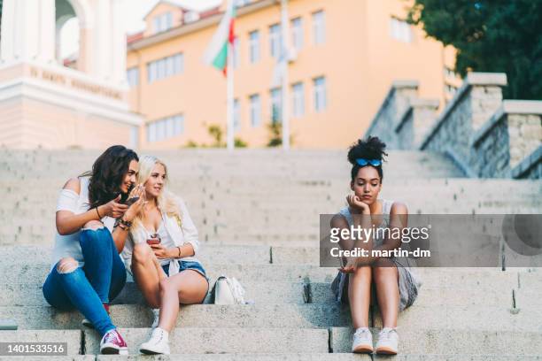 young girls gossiping about their friend - friends loneliness imagens e fotografias de stock