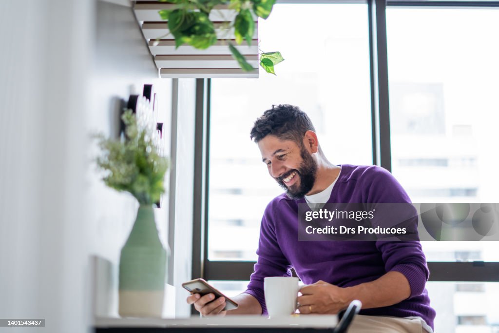 Homme latin utilisant un smartphone à la maison