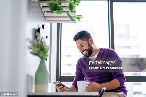 latin man using smartphone at home - lilac 個照片及圖片檔