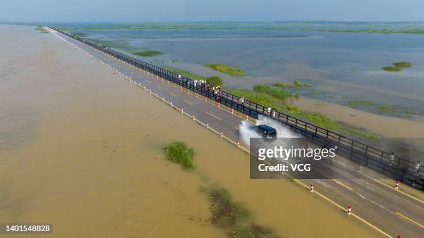 Aerial view of a vehicle being driven along a flooded road on the banks of Poyang Lake after rainfall on June 6, 2022 in Yongxiu County, Jiujiang...