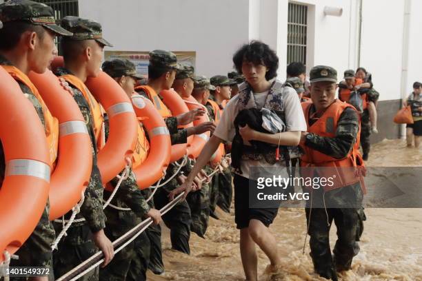 Armed police officers evacuate residents from a flood-hit area after torrential rains on June 6, 2022 in Ganzhou, Jiangxi Province of China.