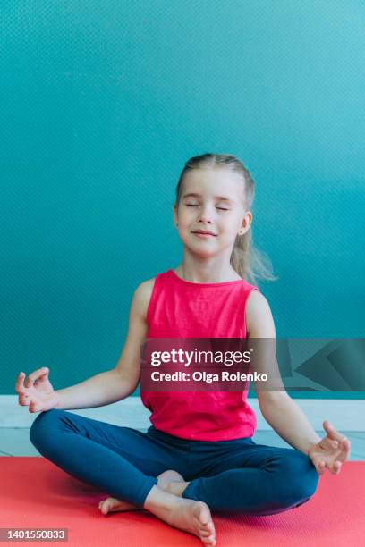 cute little fair-haired girl doing yoga in studio. sitting in lotus, padmasana pose on pink sport mat at home - self discipline imagens e fotografias de stock