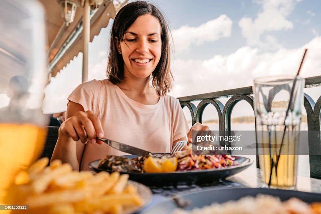 Junge Frau, die am Meer zu Mittag isst