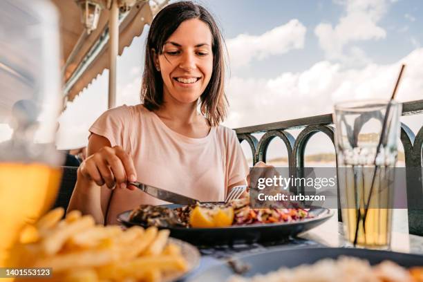 junge frau, die am meer zu mittag isst - mediterranean food stock-fotos und bilder