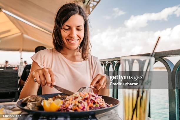 junge frau, die am meer zu mittag isst - greek food stock-fotos und bilder