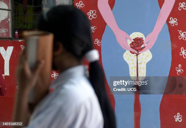 Girl walks past to a wall painting about female menstruation, at a school for underprivileged children, Parijat Academy, in Guwahati, India on May...