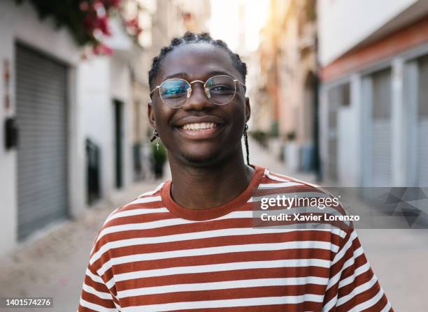 happy young african man smiling at camera outdoors - black young men stock pictures, royalty-free photos & images