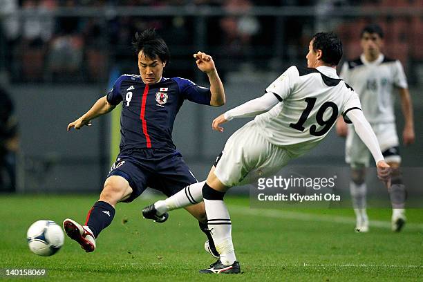 Shinji Okazaki of Japan challenges Islom Inomov of Uzbekistan during the 2014 FIFA World Cup Brazil Asian 3rd Qualifier match between Japan and...