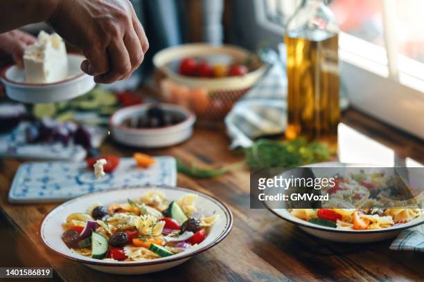 greek salad with farfalle pasta, tomato, cucumber, bell pepper, olives and feta cheese - greek salad stock pictures, royalty-free photos & images