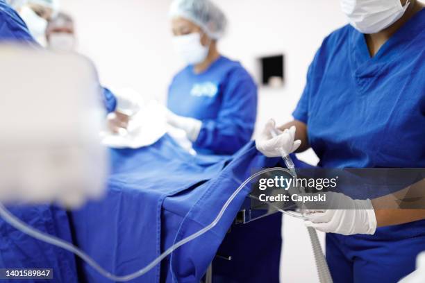 medication being applied to a catheter during a surgery - infuus stockfoto's en -beelden