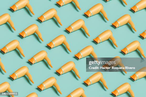 computer generated image of  many orange hair dryers on green isolated background, 3d render - haartrockner stock-fotos und bilder