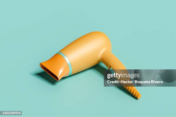 computer generated image of  many orange hair dryers on green isolated background, 3d render - hair dryer fotografías e imágenes de stock