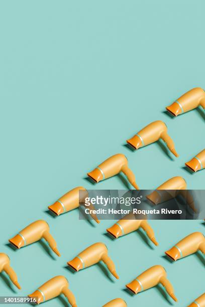 computer generated image of  many orange hair dryers on green isolated background, 3d render - hair dryer stock photos et images de collection