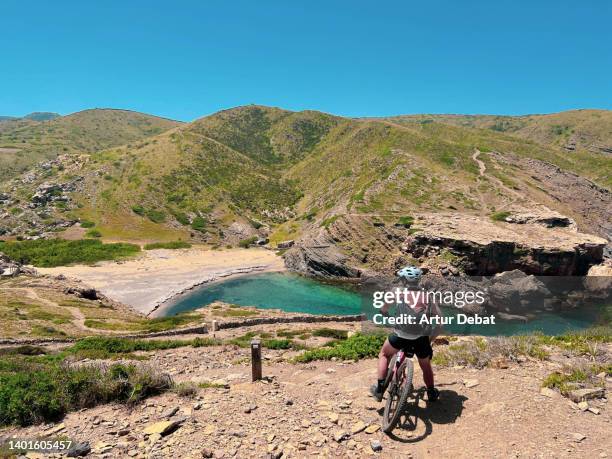 guy doing the circuit of cami de cavalls in the menorca island with mountain bike. - cavalls stock pictures, royalty-free photos & images