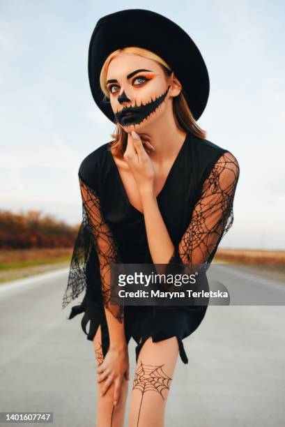 girl in a hat and halloween makeup on the road. halloween. sunset. - blue eyed soul stock pictures, royalty-free photos & images
