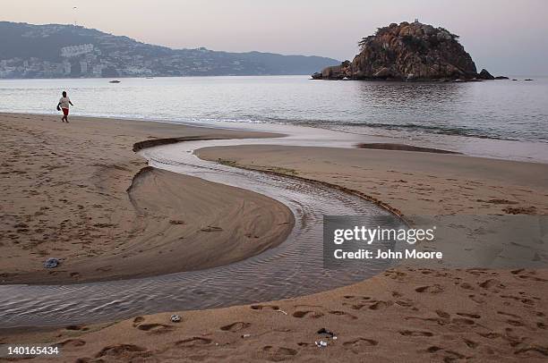 Lone person walks along the beach before sunrise on February 29, 2012 in Acapulco, Mexico. One of Mexico's top tourist destinations, Acapulco has...