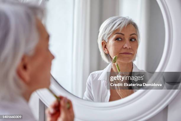 woman with mirror massaging face - facial hair stock pictures, royalty-free photos & images