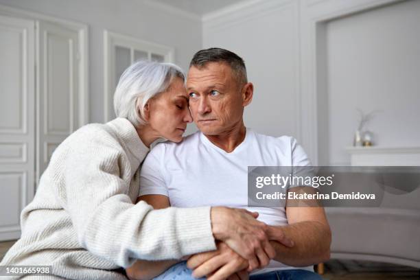 older frustrated couple sit on sofa at home - man looking upset fotografías e imágenes de stock