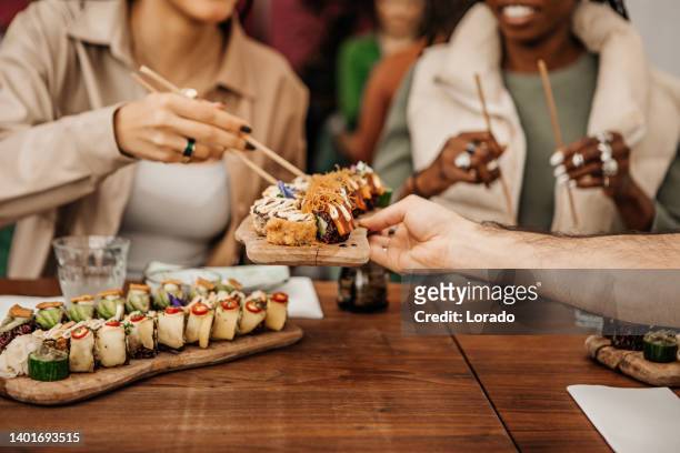 amigos disfrutando compartiendo sushi vegano en un restaurante local - comida japonesa fotografías e imágenes de stock