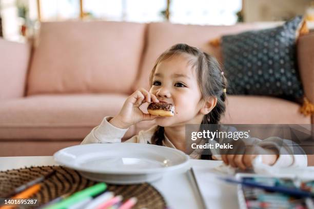 cute little girl eating chocolate doughnut - biting donut stock pictures, royalty-free photos & images