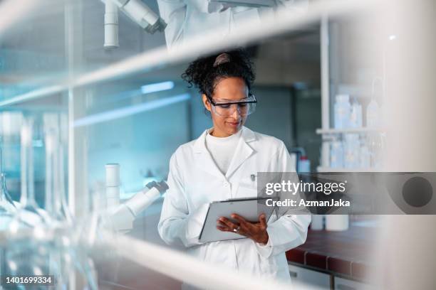 junge wissenschaftlerin notiert ergebnisse des experiments in einem labor - laborkittel stock-fotos und bilder