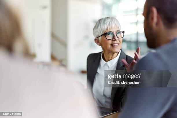 agente assicurativo femminile che parla con i suoi clienti durante una riunione in ufficio. - candid business foto e immagini stock