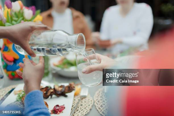 close up man pouring water from carafe at patio table - karaffin bildbanksfoton och bilder