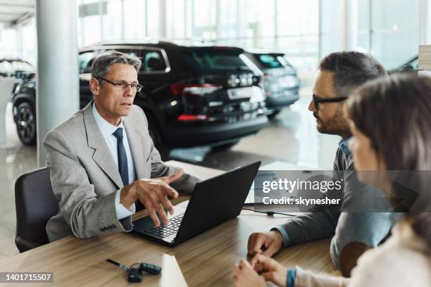 car salesperson talking to a couple in a showroom. - buying a car 個照片及圖片檔