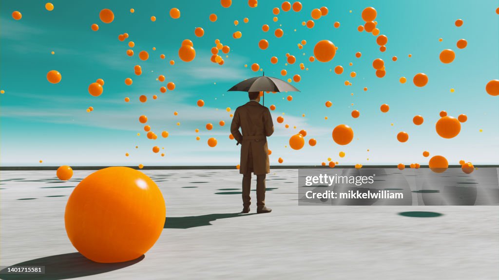 Orange balls fall from the sky while man with umbrealla looks at them