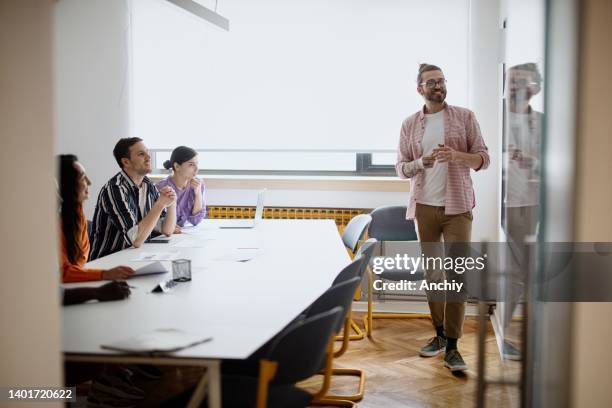 young businessman giving presentation to colleagues - presentation template stock pictures, royalty-free photos & images