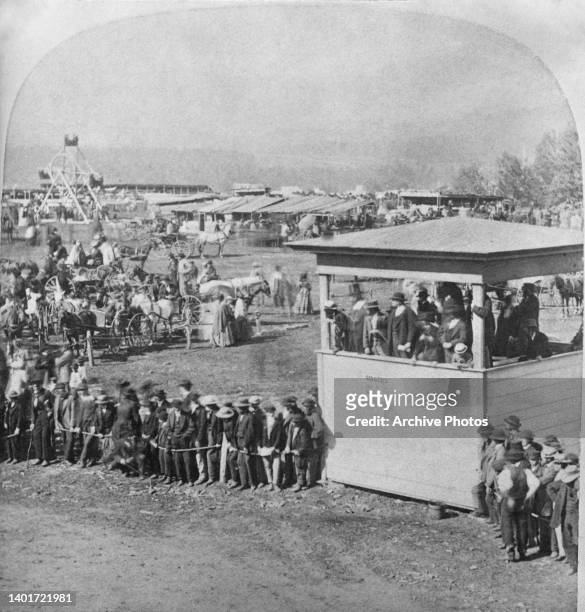 Spectators stand behind a rope barrier and on a raised observation tower on the site of the Lamoille County Fair in Morrisville, Lamoille County,...