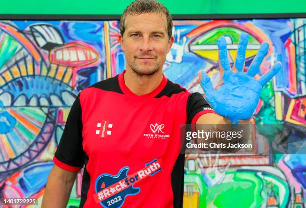 Bear Grylls puts his hand print on a Painting by Sacha Jafri during the Ruth Strauss Foundation's #RockforRuth event at The Wormsley Estate on June...