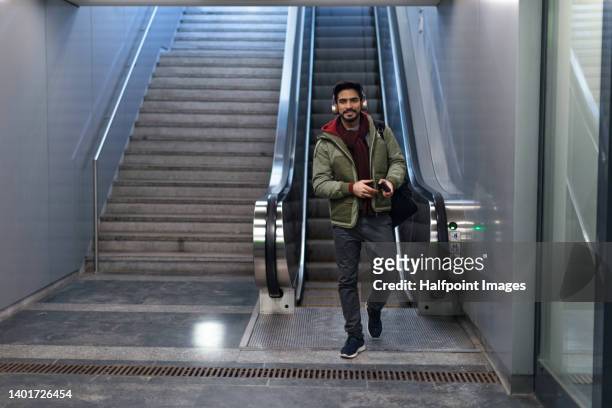 young middle eastern man commuter in subway, escalator in background. - 通勤電車 ストックフォトと画像