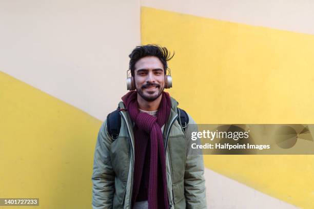 young handsome cheerful man standing in front of colourful wall in the street, smiling and looking at camera. - handsome muslim men stock pictures, royalty-free photos & images