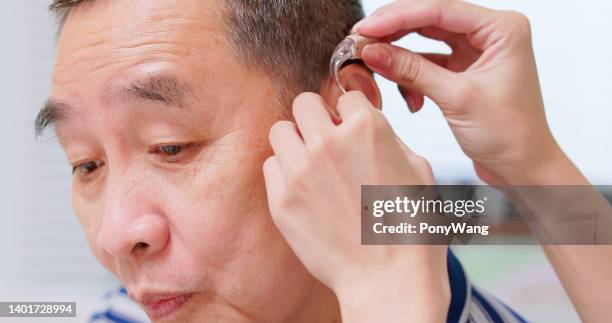 help patient wear hearing aid - hearing aids stock pictures, royalty-free photos & images