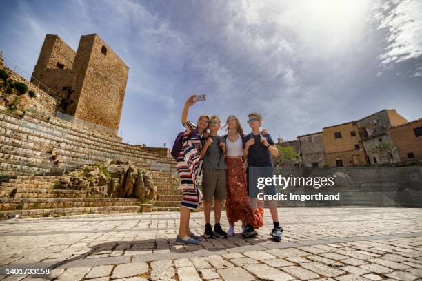 mother and teenagers sightseeing teatro pietra rosa in town of pollina - boys mobile phone group stock pictures, royalty-free photos & images