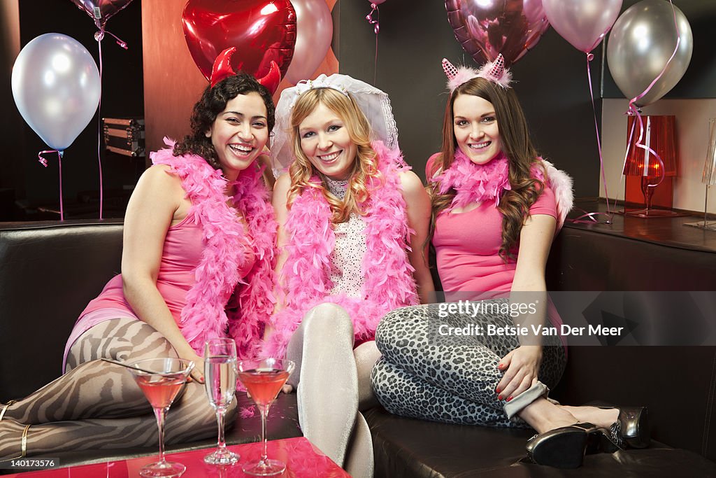 Three women in hen night outfits in nightclub.