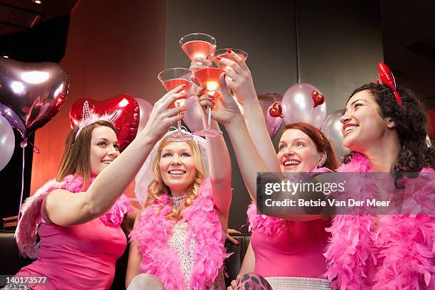 women toasting cocktails at hen night party. - pink boa stock pictures, royalty-free photos & images