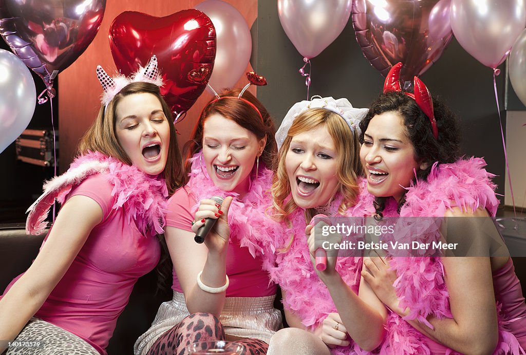 Women singing karaoke at hen night party.