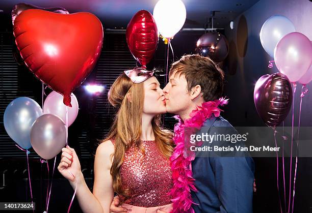 couple kissing, woman holding heartshaped balloon. - an evening with heart fotografías e imágenes de stock